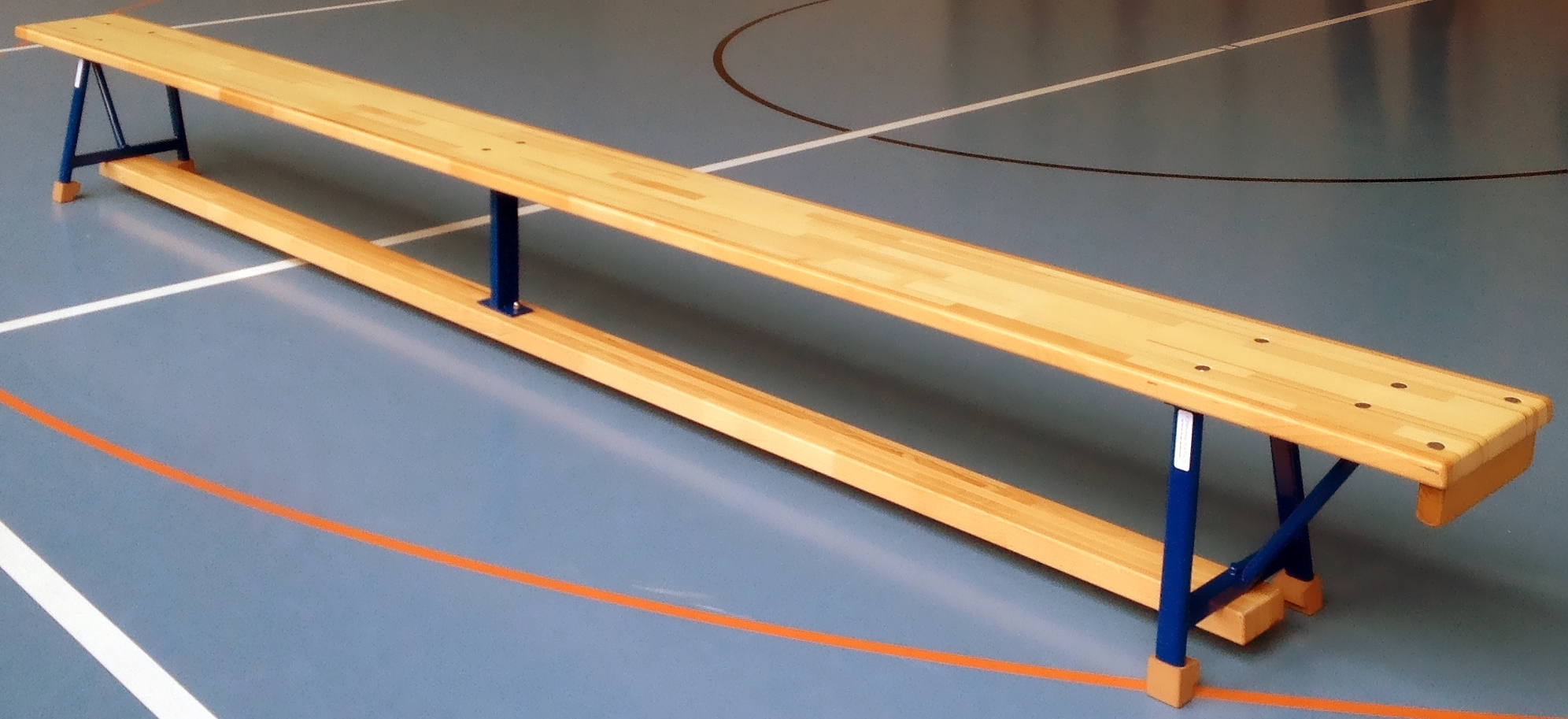 Lange Turnhallenbank aus Holz mit blauem Metallgestell auf einem Hallensportplatz