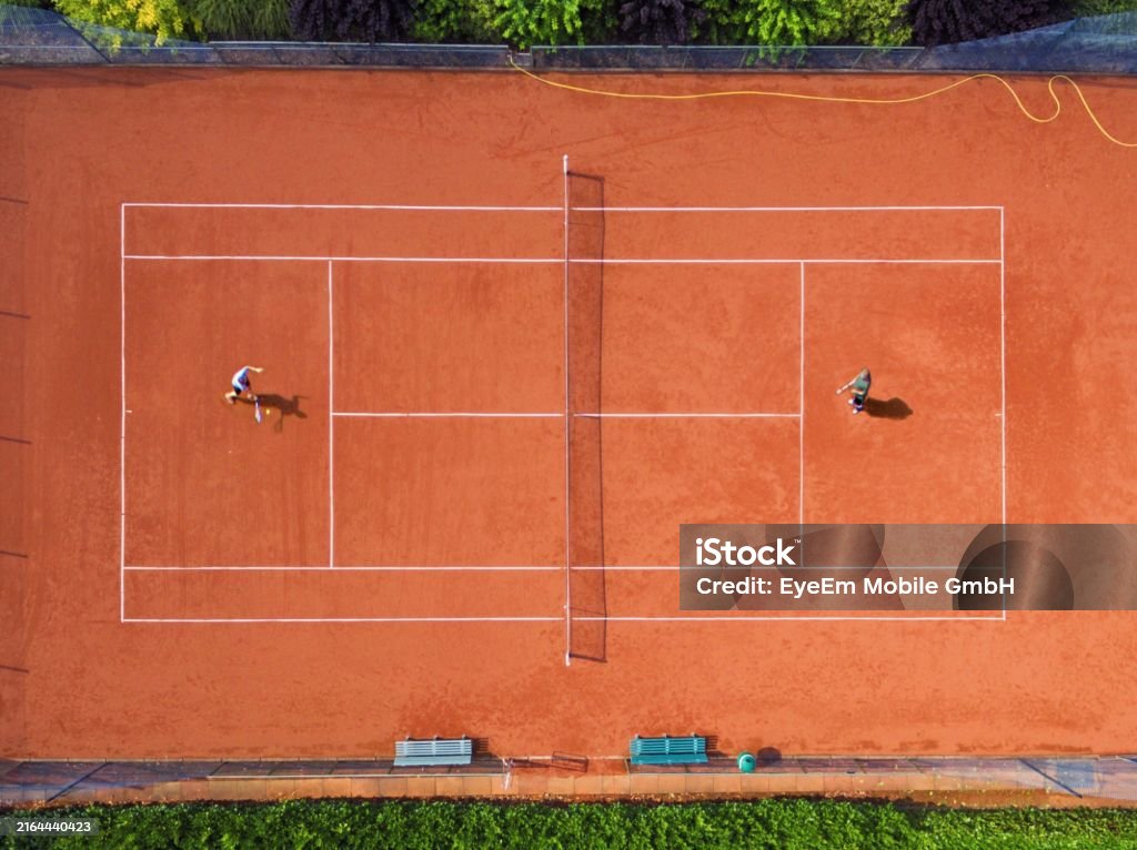 Zwei Personen spielen Tennis auf einem Sandplatz aus der Vogelperspektive