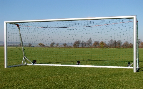 Ein großes Fußballtor auf einem grünen Rasen mit klarem Himmel im Hintergrund