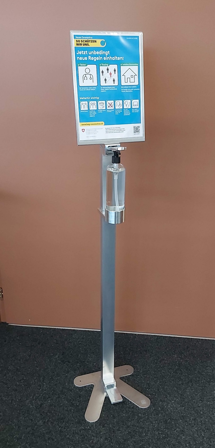 Ein Desinfektionsmittelspender mit einem Schild, das Hinweise zur Einhaltung neuer Hygiene- und Verhaltensregeln gibt.