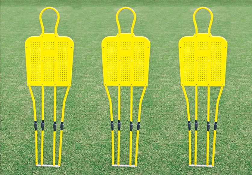 Drei gelbe Fußballtrainings-Dummies auf einem grünen Spielfeld für Übungen