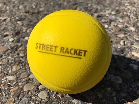 Nahaufnahme eines gelben Street Racket Balls auf Asphalt