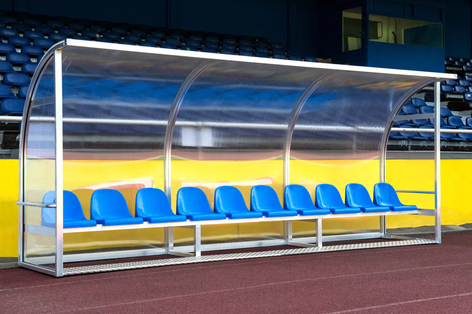Blaue Trainerbank mit Schutzdach auf einem Sportplatz