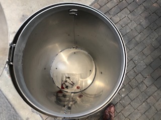 Innenansicht eines leeren Edelstahltanks auf gepflastertem Boden