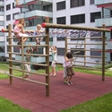 Mehrere Kinder klettern und spielen auf einem Klettergerüst in einem Wohngebiet. Das Gerüst besteht aus Holz und bietet verschiedene Klettermöglichkeiten.